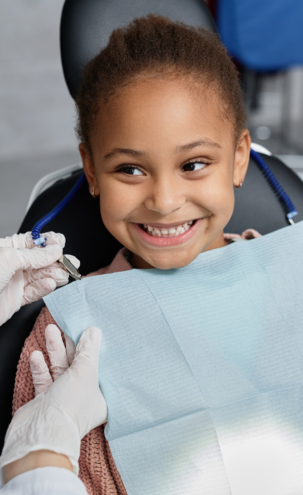 North Seattle Smiles | young girl smiling on dental chair holding a teddy bear